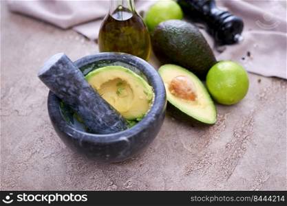 making guacamole - fresh sliced avocado in marble mortar on grey concrete table.. making guacamole - fresh sliced avocado in marble mortar on grey concrete table