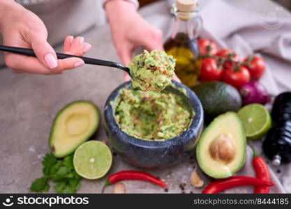 making guacamole - woman holding spoon with mixed minced ingredients.. making guacamole - woman holding spoon with mixed minced ingredients