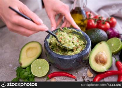 making guacamole - woman holding spoon with mixed minced ingredients.. making guacamole - woman holding spoon with mixed minced ingredients
