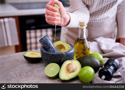 making guacamole - woman squeezing fresh lime juice into marble mortar with avocado.. making guacamole - woman squeezing fresh lime juice into marble mortar with avocado