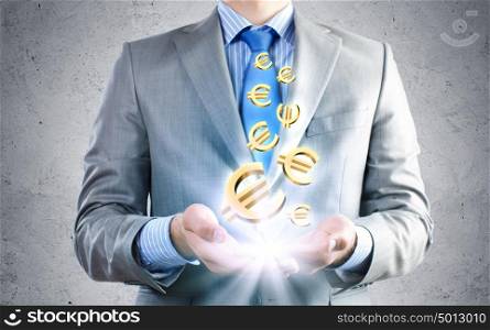 Making money. Close up of businessman holding euro symbols in palms