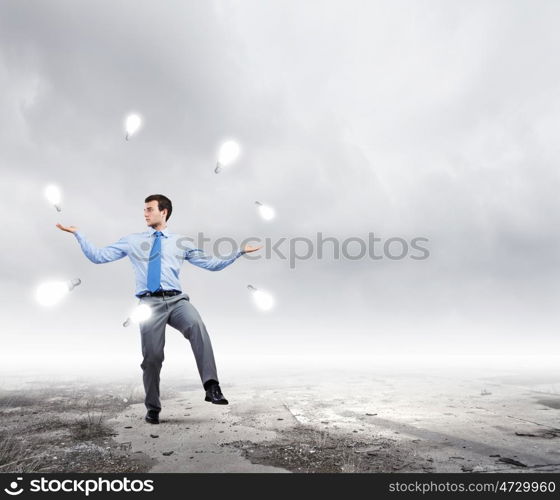 Making money. Young businessman juggling with currency symbols against city background