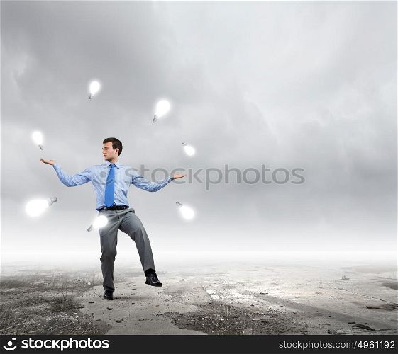Making money. Young businessman juggling with currency symbols against city background