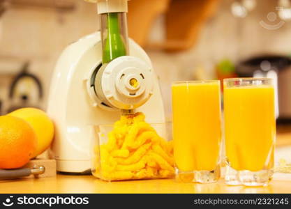 Making orange juice nutritious vitamin packed drink in juicer machine at home in kitchen. Healthy eating, vegetarian food, dieting concept. Making orange juice in juicer machine in kitchen