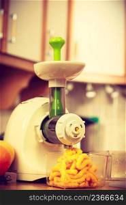 Making orange juice nutritious vitamin packed drink in juicer machine at home in kitchen. Healthy eating, vegetarian food, dieting concept. Making orange juice in juicer machine in kitchen