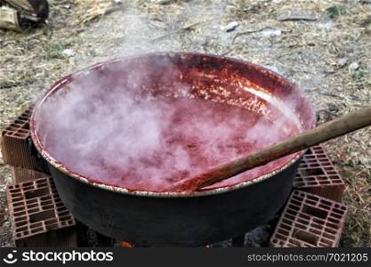 Making organic tomato sauce in big pot, traditional village tomato paste on wood fire