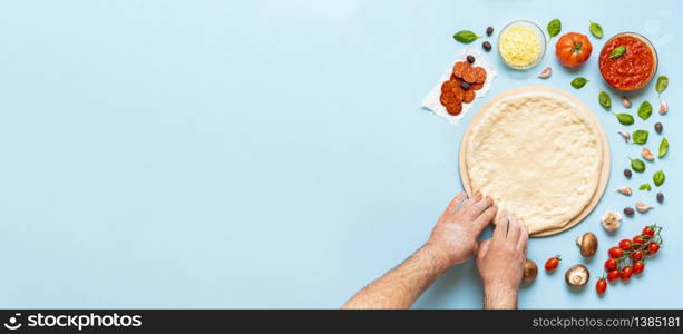 Making pizza step by step, man&rsquo;s hands stretching the dough on a pizza stone. Pizza ingredients directly on the table. Kneading pizza dough top view.