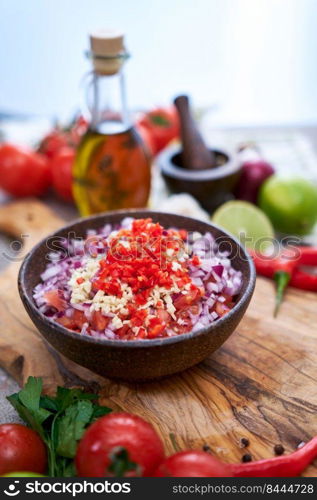 making salsa dip sauce - chopped garlic, tomatoes and onion in wooden bowl.. making salsa dip sauce - chopped garlic, tomatoes and onion in wooden bowl