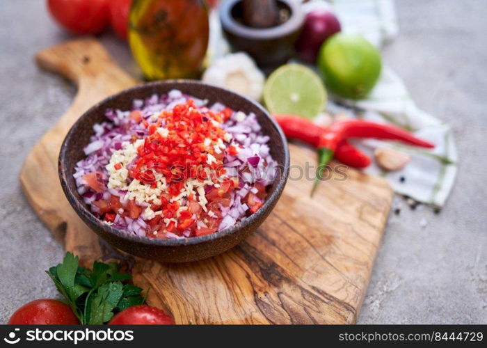 making salsa dip sauce - chopped garlic, tomatoes and onion in wooden bowl.. making salsa dip sauce - chopped garlic, tomatoes and onion in wooden bowl