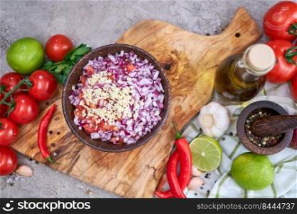 making salsa dip sauce - chopped garlic, tomatoes and onion in wooden bowl.. making salsa dip sauce - chopped garlic, tomatoes and onion in wooden bowl