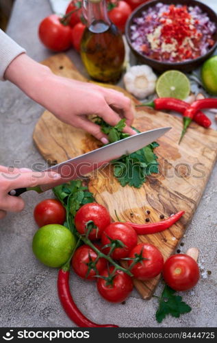 making salsa dip sauce - woman cutting and chopping cilantro or parsley on wooden cutting board.. making salsa dip sauce - woman cutting and chopping cilantro or parsley on wooden cutting board