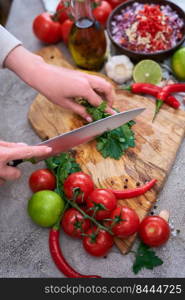 making salsa dip sauce - woman cutting and chopping cilantro or parsley on wooden cutting board.. making salsa dip sauce - woman cutting and chopping cilantro or parsley on wooden cutting board