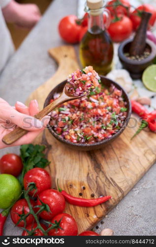 making salsa dip sauce - woman mixing chopped ingredients in wooden bowl.. making salsa dip sauce - woman mixing chopped ingredients in wooden bowl