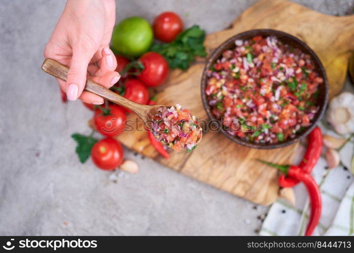 making salsa dip sauce - woman mixing chopped ingredients in wooden bowl.. making salsa dip sauce - woman mixing chopped ingredients in wooden bowl