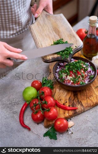 making salsa dip sauce - woman pouring chopped cilantro or parsley to wooden bowl.. making salsa dip sauce - woman pouring chopped cilantro or parsley to wooden bowl