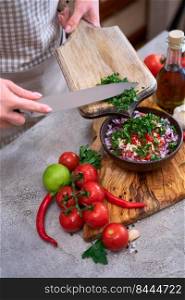 making salsa dip sauce - woman pouring chopped cilantro or parsley to wooden bowl.. making salsa dip sauce - woman pouring chopped cilantro or parsley to wooden bowl