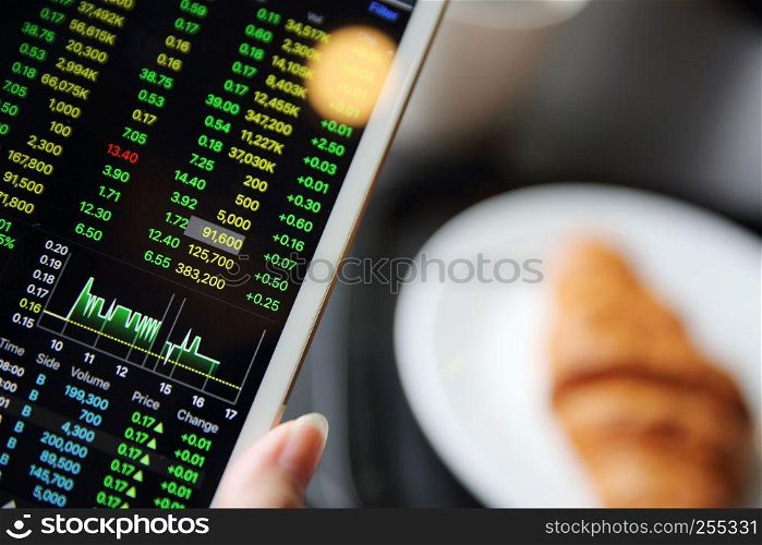 Making trading online on the tablet with business woman hand and croissant