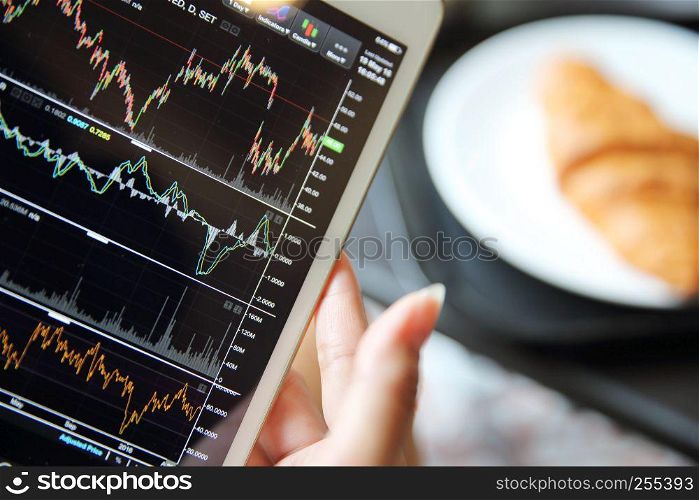 Making trading online on the tablet with business woman hand and croissant