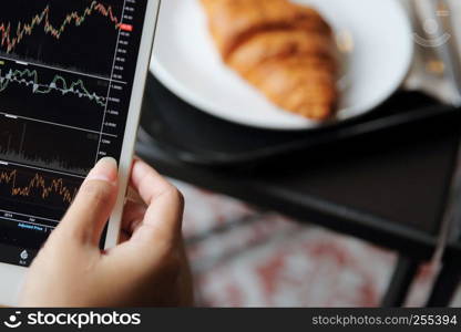 Making trading online on the tablet with business woman hand and croissant