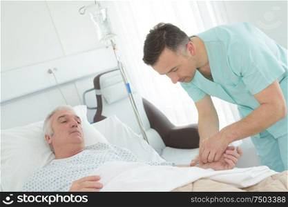 mal nurse visiting senior patient in hospital