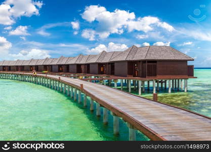 MALDIVES - JUNE 24, 2018: Water Villas (Bungalows) and wooden bridge at Tropical beach in the Maldives at summer day