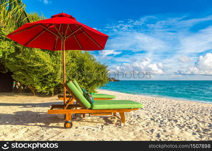 MALDIVES - JUNE 24, 2018: Wooden sunbed and umbrella on tropical beach in the Maldives at summer day