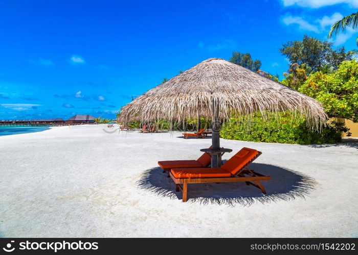 MALDIVES - JUNE 24, 2018: Wooden sunbed and umbrella on tropical beach in the Maldives at summer day