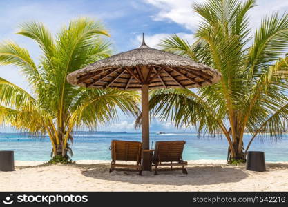 MALDIVES - JUNE 24, 2018: Wooden sunbed and umbrella on tropical beach in the Maldives at summer day