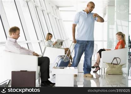 Male airline passenger waiting with other passengers in departure gate