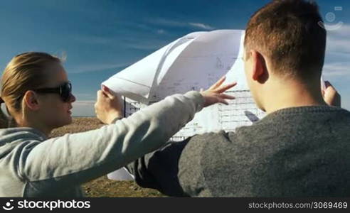 Male and female architects exploring open territory talking about their construction project before