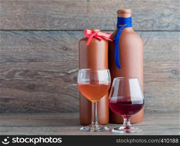 Male and female balm two glasses on a background of clay bottles of balm marked tie and a butterfly on the background of wood.. Two balsam bottle and two filled glasses on the wooden background