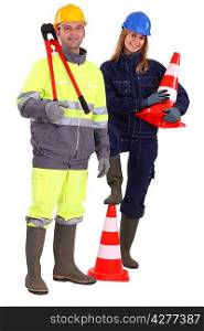 male and female bricklayers posing with construction cones