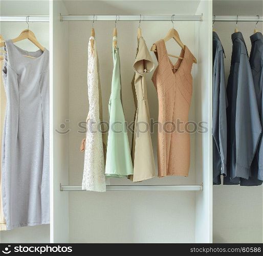 Male and female clothes hanging on hangers in wardrobe