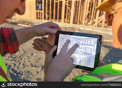 Male and Female Construction Workers Reviewing Kitchen Drawing on Computer Pad at Construction Site.
