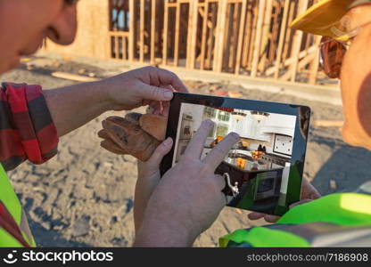 Male and Female Construction Workers Reviewing Kitchen on Computer Pad at Construction Site.
