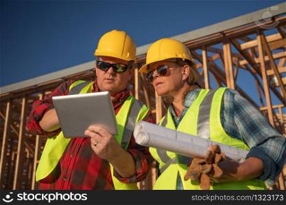 Male and Female Construction Workers Using Computer Pad at Construction Site.