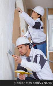 male and female contractors plastering an interior wall