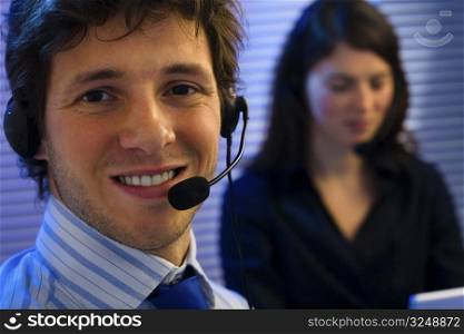Male and female customer service representative working in office, smiling.