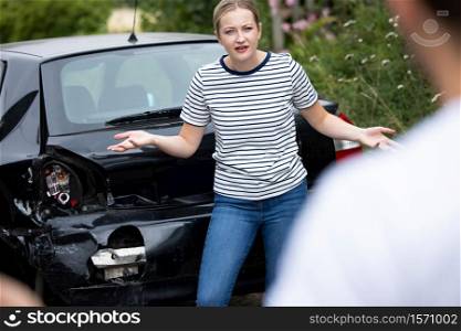 Male And Female Drivers Arguing Over Damage To Cars After Accident