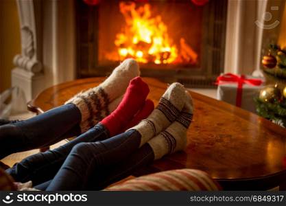 Male and female feet in woolen socks warming at burning fireplace