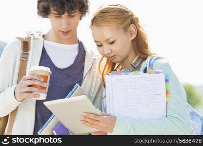 Male and female friends using digital tablet at college campus
