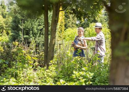 Male and female gardeners discussing over plants at plant nursery