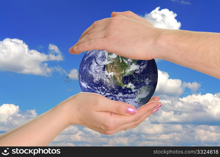 male and female hands holding the earth on background the sky