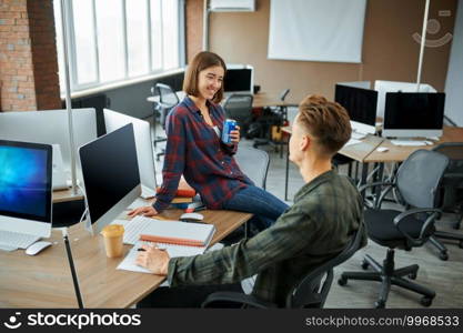 Male and female IT specialists talks in office. Web programmer or designer at workplace, creative occupation. Modern information technology, corporate team. Male and female IT specialists talks in office