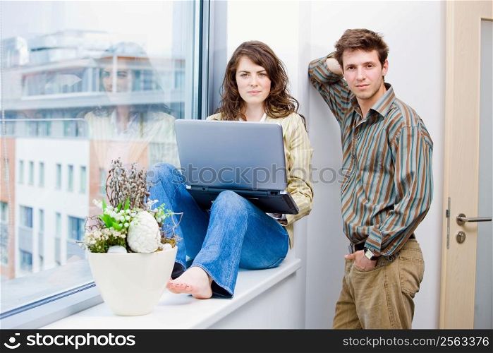 Male and female office workers talking and brainstorming at office, using laptop computer.