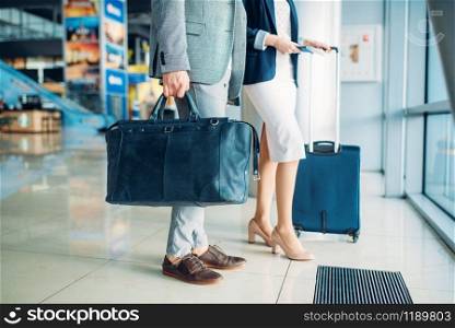 Male and female passengers with luggage in airport, business trip. Businessman and businesswoman in air terminal, negotiation travel
