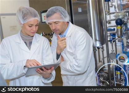 male and female quality control technicians looking at tablet