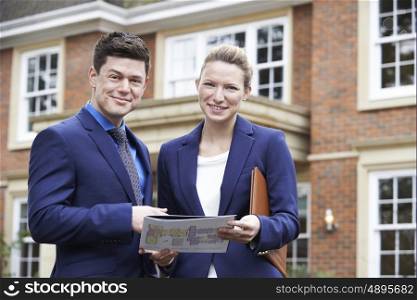 Male And Female Realtor Standing Outside Residential Property