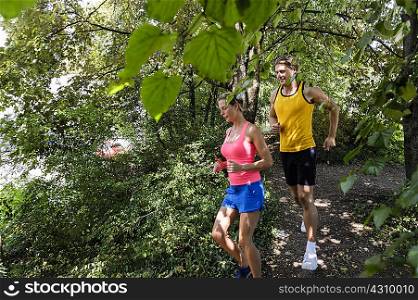 Male and female running through wooded park