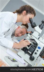 male and female scientists using microscopes in laboratory